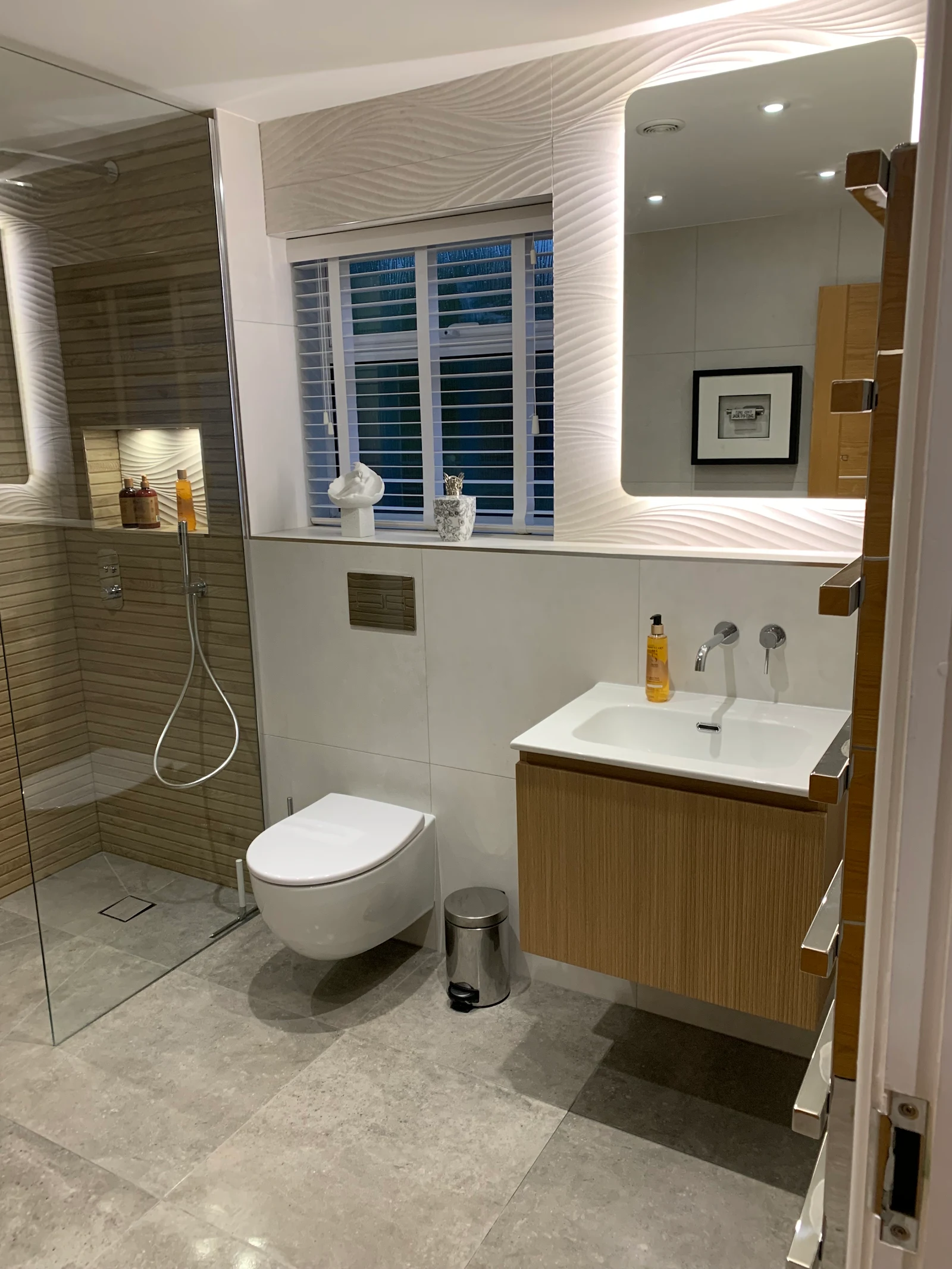 Contemporary bathroom with oak vanity unit and backlit mirror