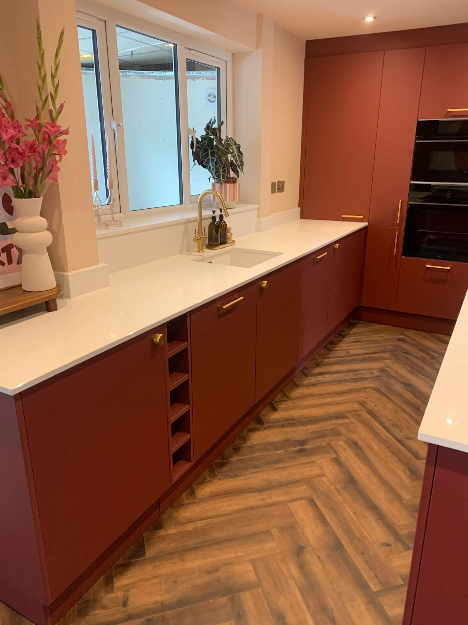 Deep red kitchen with white worktops and herringbone floor