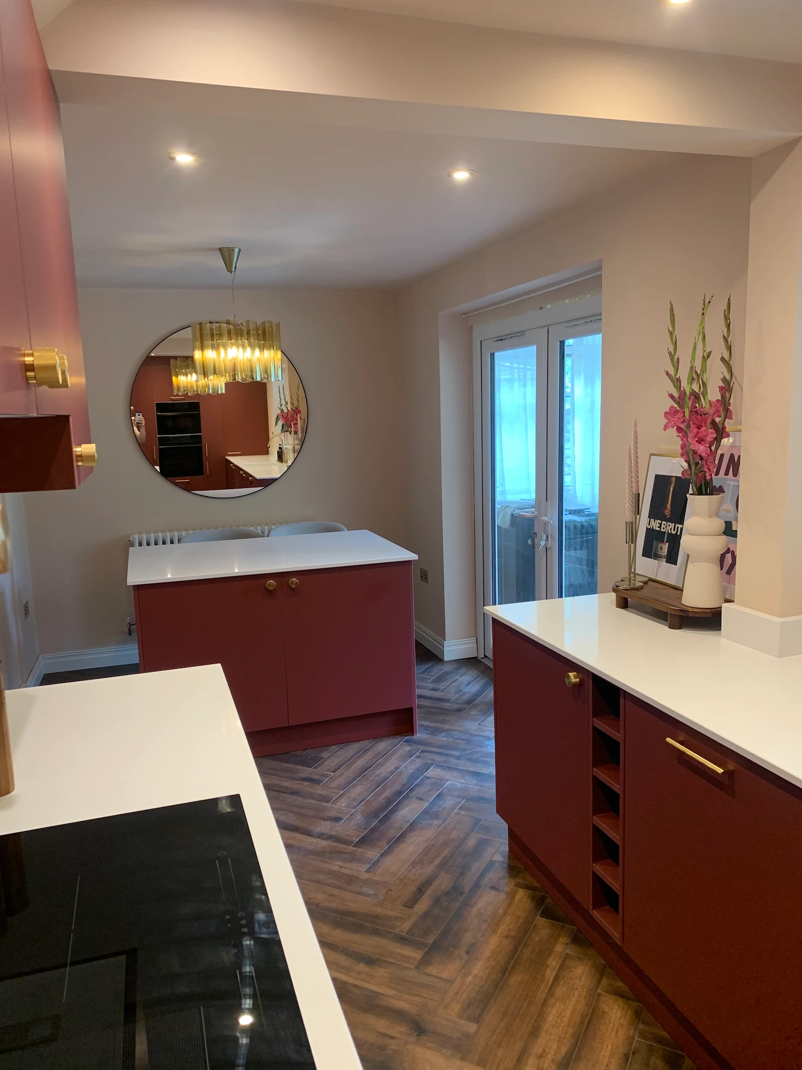 Terracotta kitchen with round brass mirror and herringbone flooring