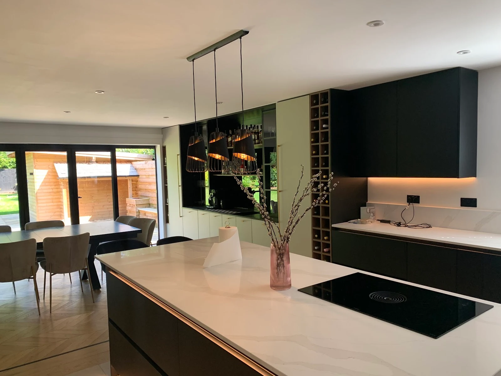 A completed contemporary matt-black kitchen with a marble waterfall island by Best Kitchens