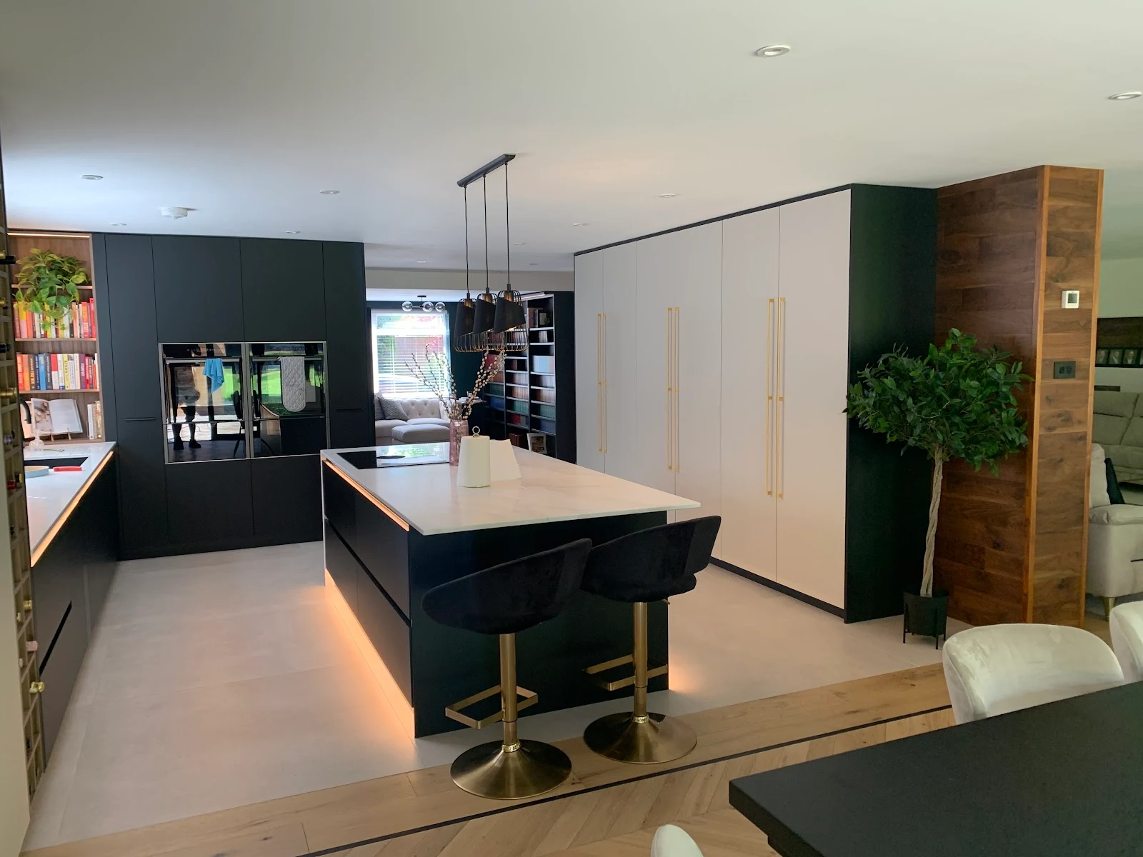 Black kitchen with built-in bar, wine storage and brass bar stools
