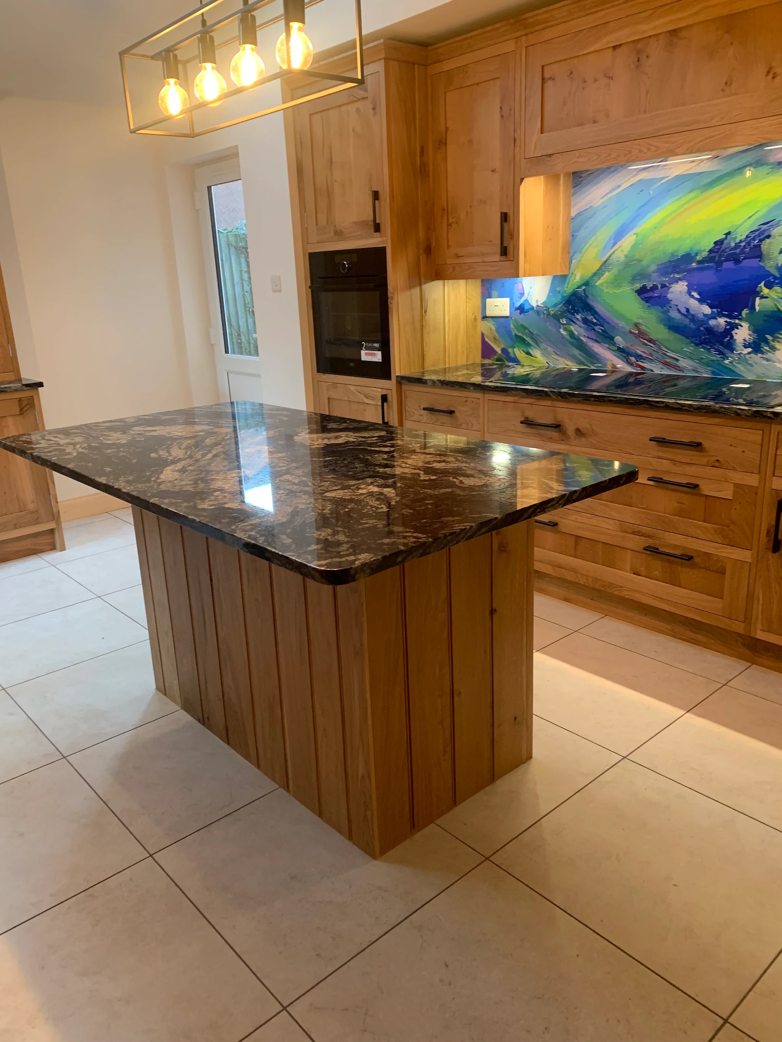 Solid oak kitchen with black granite and a hand-painted glass wave splashback